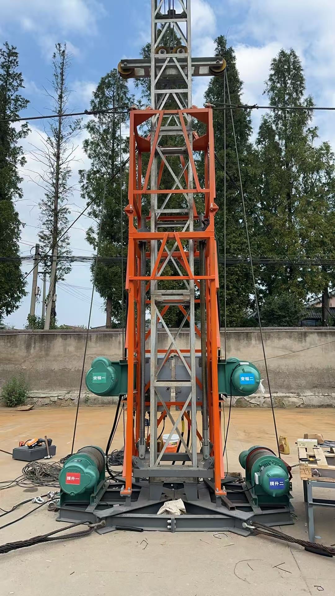 Fabricated lifting cage. Vertical lead screws sit inside the orange frame; luffing motors are on the two sides.